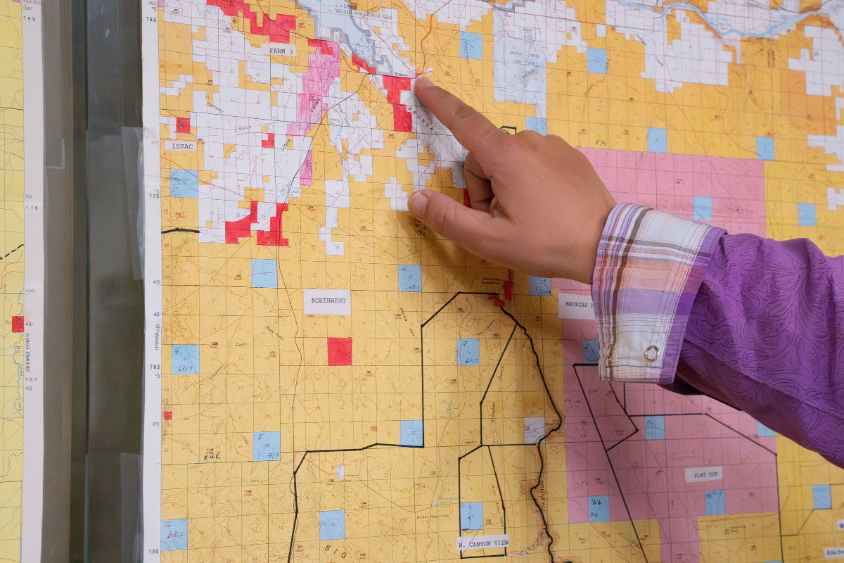 Woman’s fingers point to place on map.