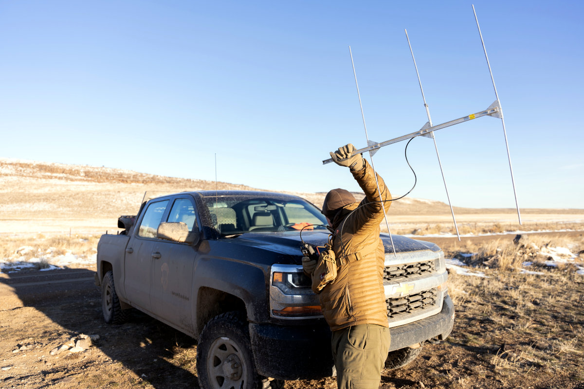 Man in winter clothing holds radio antennae.