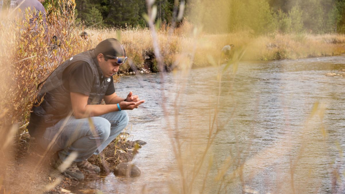 A person examining rocks near a river.