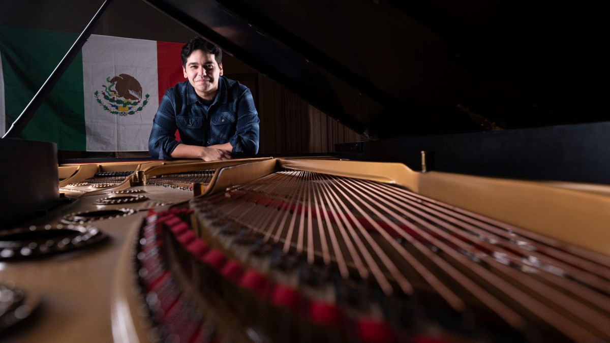 Alex Aguilar leaning against a grand piano.