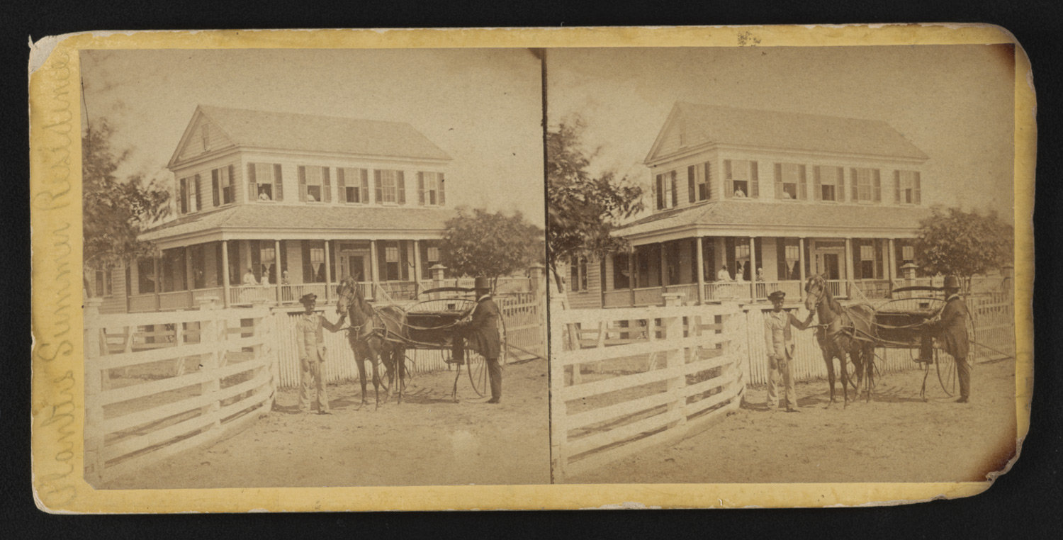 an African American boy holding on to the horse drawn carriage in front of a planter's house. A man prepares to board the carriage.